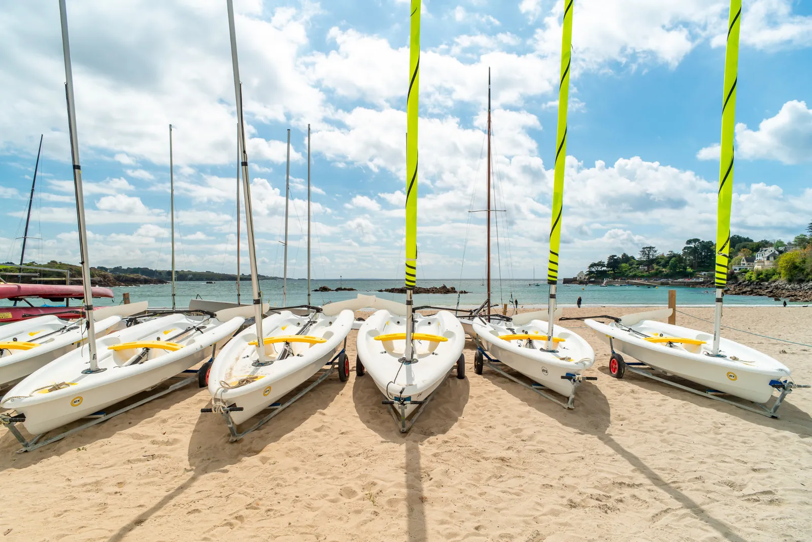 Dériveurs de l'école de voile alignés sur le sable