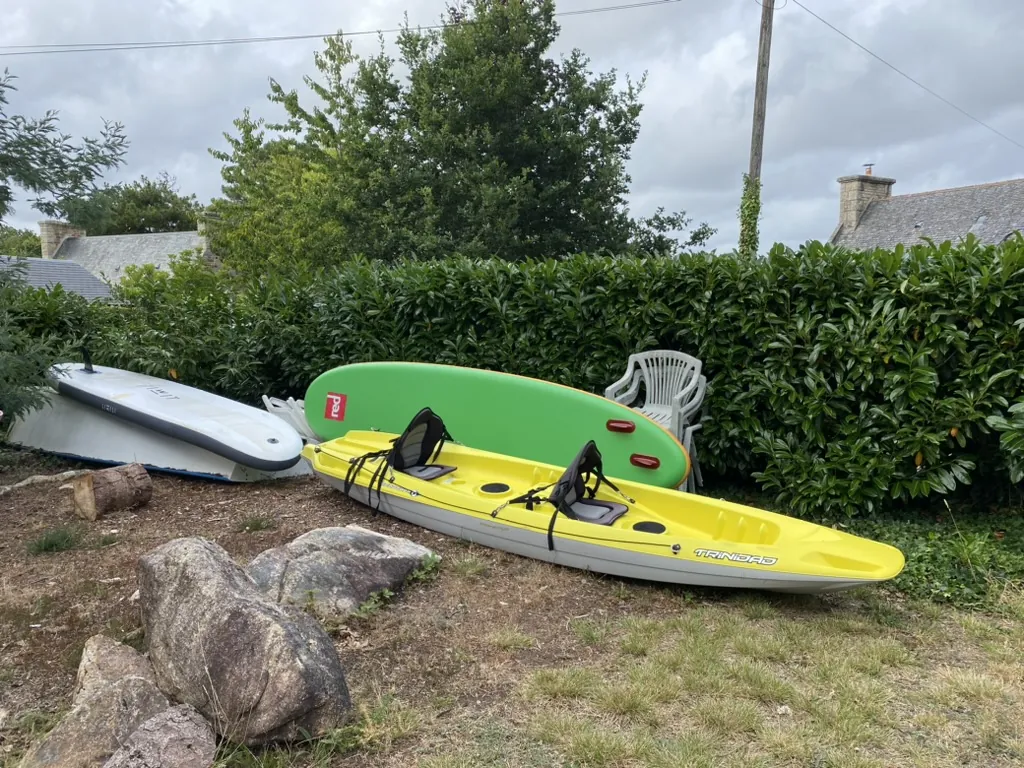Deux paddles gonflables et un kayak posés dans le jardin de la maison