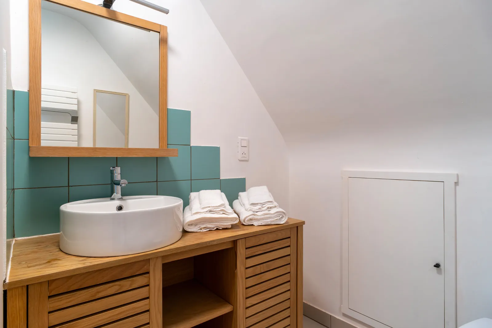 Salle d'eau carrelée verte, lavabo et miroir